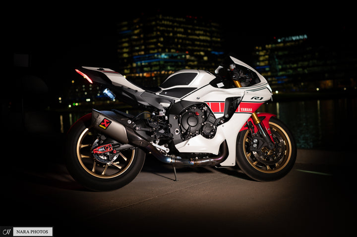 White and red Yamaha R1 sportbike parked at night with a city skyline
